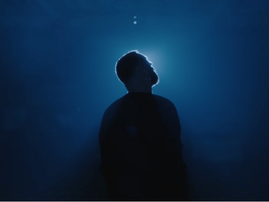 Silhouette of Sam Smith standing against a deep blue background