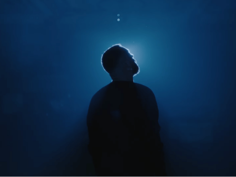 Silhouette of Sam Smith standing against a deep blue background