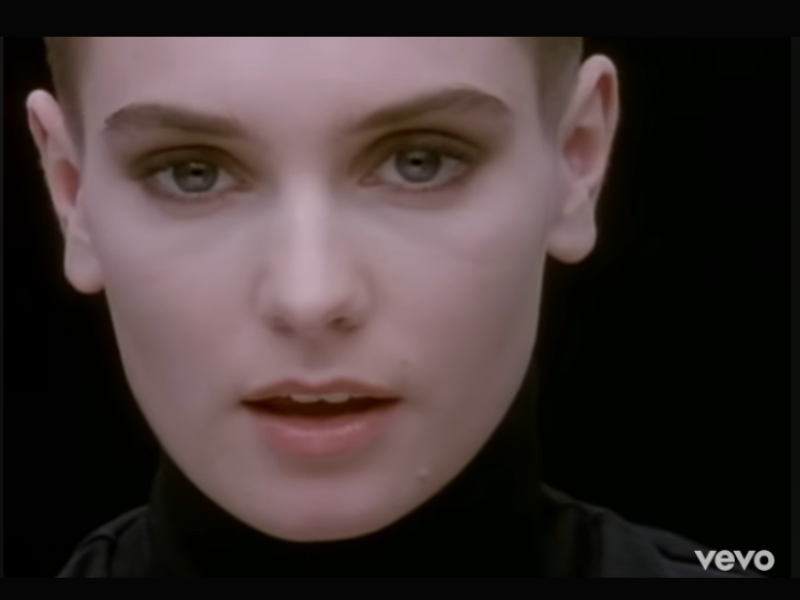Sinead O'Connor wearing a black polar neck top.png
