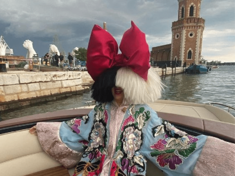 Singer Sia wearing a giant red bow on her head