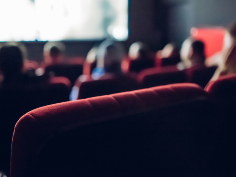 Small movie theatre with people seated watching a movie