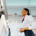 Smiling flight attendant in uniform standing in the aircraft