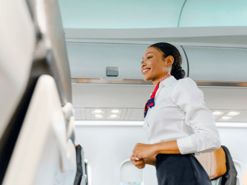Smiling flight attendant in uniform standing in the aircraft
