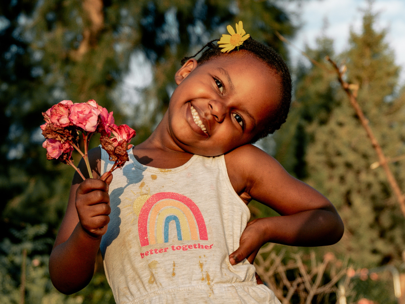 Smiling girl in white dress holding bouquet of flowers