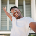 Smiling young Black man in front of a new home