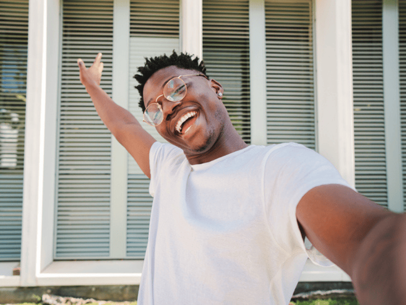 Smiling young Black man in front of a new home
