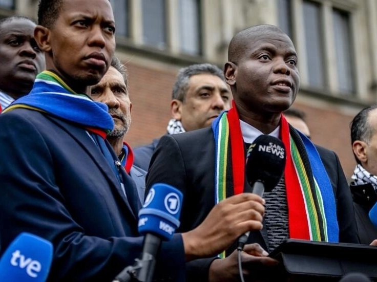 South Africa's Minister of Justice Ronald Lamola (R) talks to reporters after the first day of hearings in a case Israel and its US ally have derided