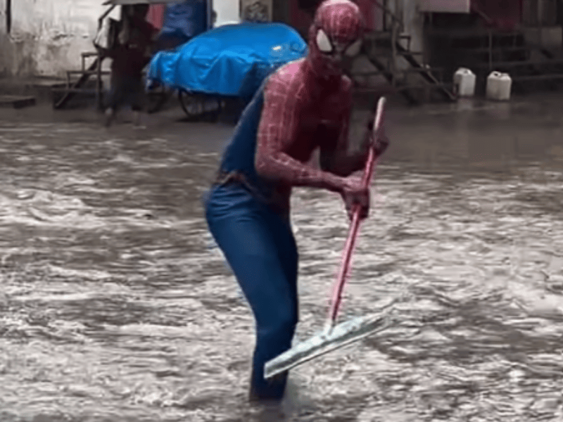 Spiderman uses a mop in a flooded space in Mumbai street