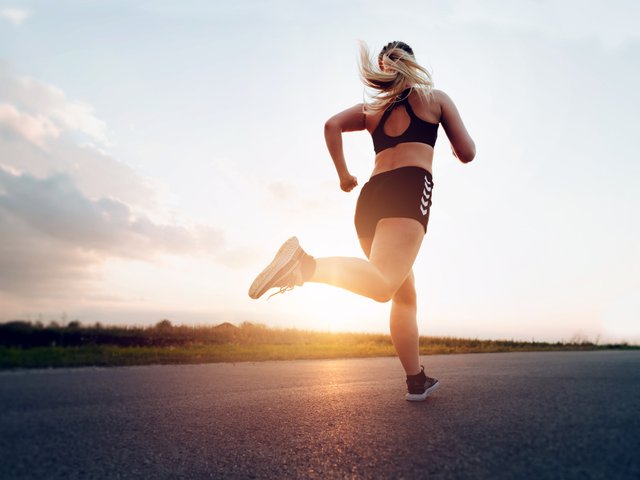 Sporty woman running at sunset on the road