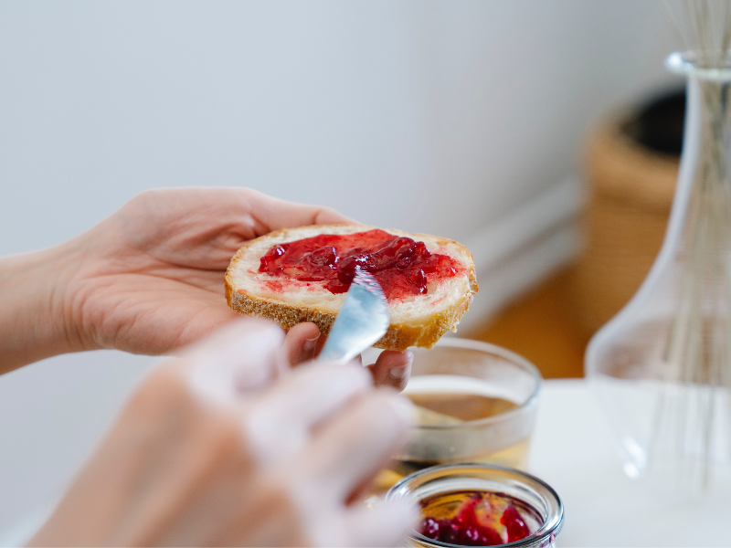 Spreading strawberry jam on bread