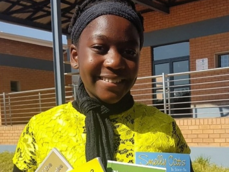 Stacey Fru posing with her authored books
