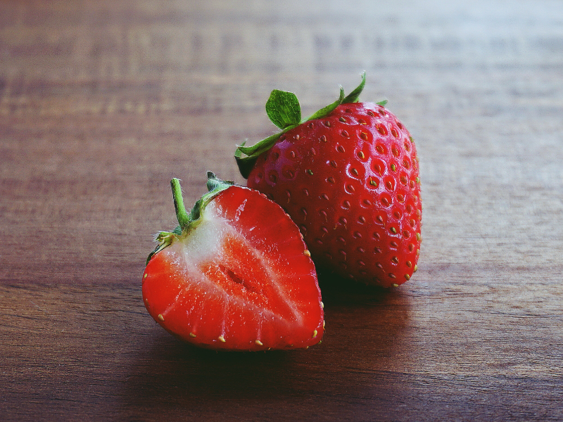 Strawberry cut in half on a brown surface