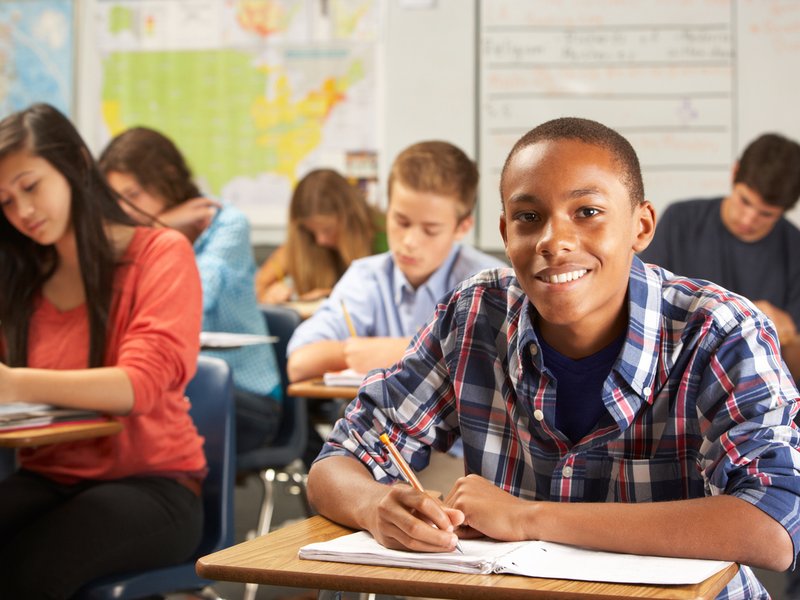 Student writing on notebook in classroom