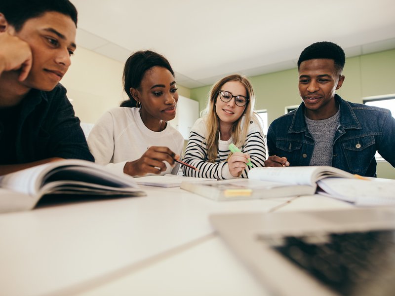 Students studying with books in classroom