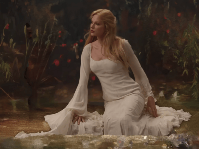 Taylor Swift wearing a long white dress with long sleeves