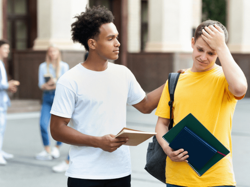 Teenage boy consoles fellow learner after receiving exam results