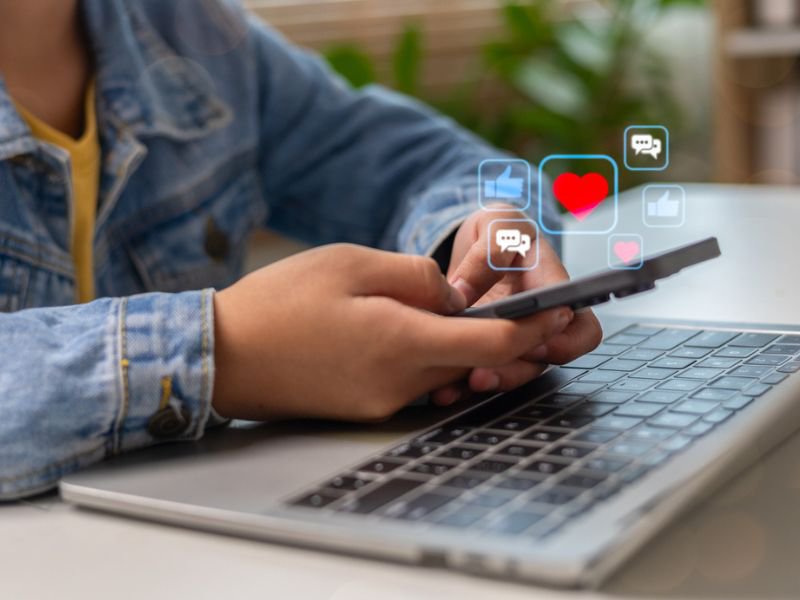 Teenager holding phone over laptop