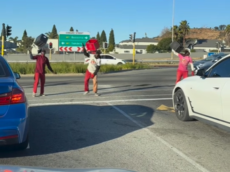 Three men perform a dance routine at the traffic lights in South Africa