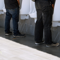 Three men standing at urinals at a public toilet