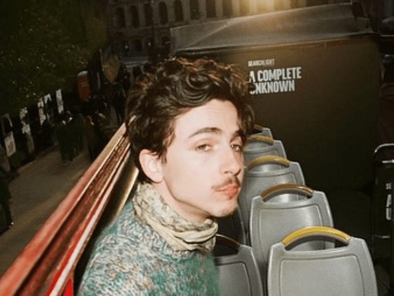 Timothee Chalamet sitting on an open air bus at night