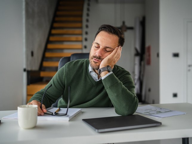 Tired man sleeping at office desk feeling burnt out