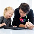 Toddler girl in child occupational therapy session doing playful exercises on a digital tablet with her therapist