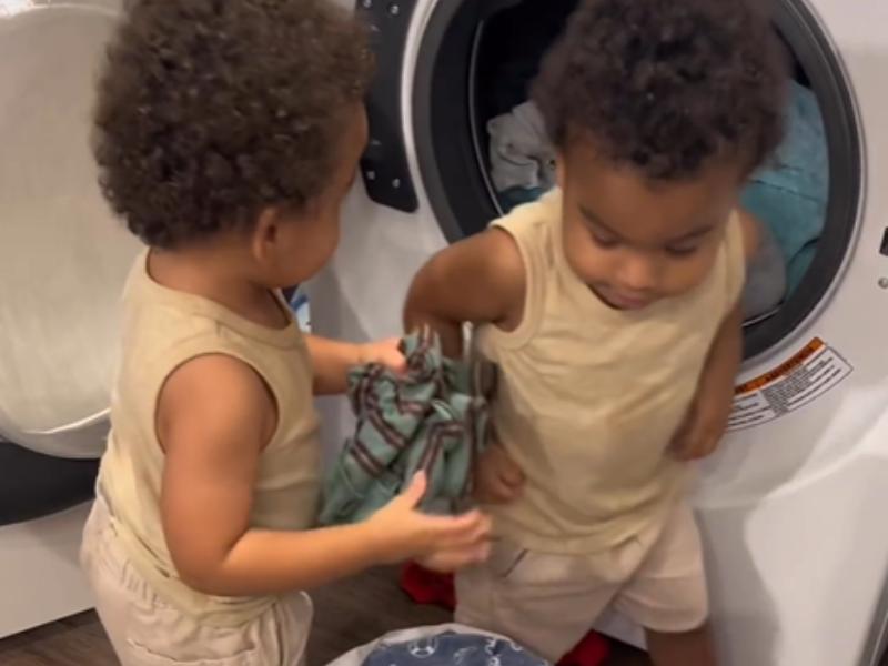 Twins loading their laundry into the washing machine