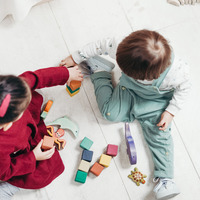 Two children sitting down and playing with blocks