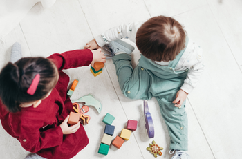 Two children sitting down and playing with blocks