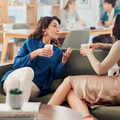 Two friends at work chat with one another on a coffee break