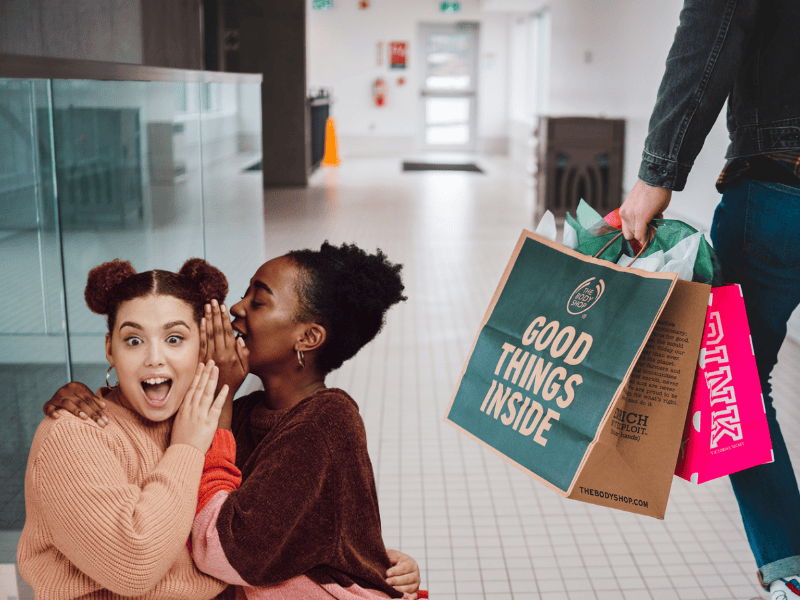 Two friends share a secret with one another about a guy nearby