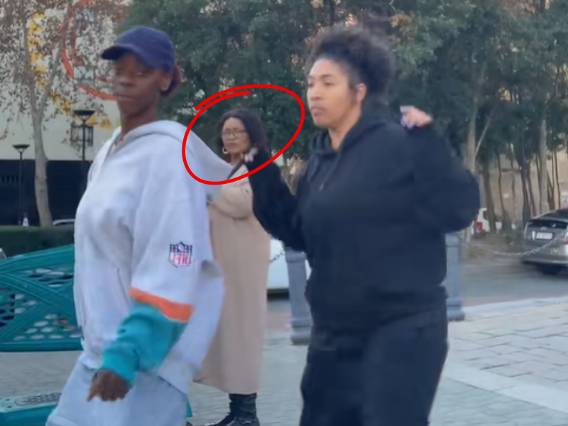 Two girls dancing on a roadside in Sandton and a lady watches them