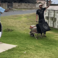 Two guys dancing on the street side playing music off speakers inside a wheelbarrow