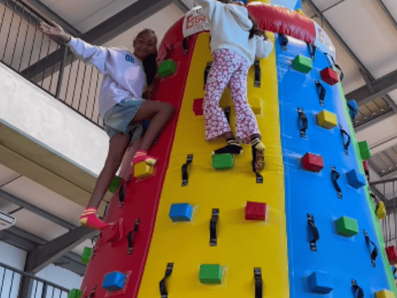 Two kids climb up a bouncy climbing wall in Ballito