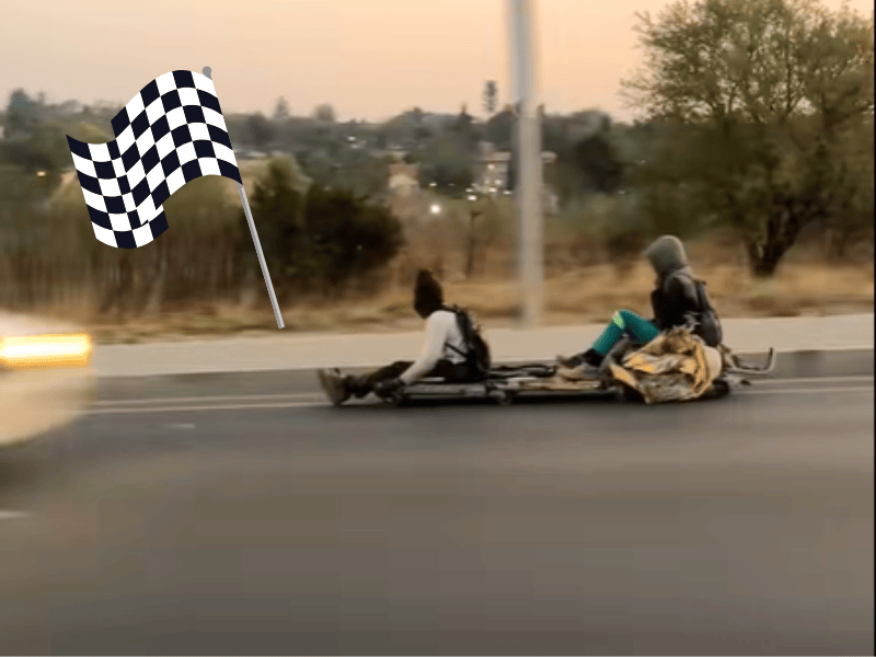 Two men riding a bobsleigh on the road look like F1 drivers