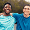 Two men pose outdoors with their arms around