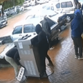 Two men wheel an ice cream machine away from a store toward a van