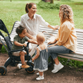Two moms sitting on a park bench with their children