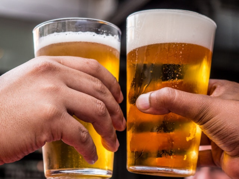 Two persons holding drinking glasses filled with beer