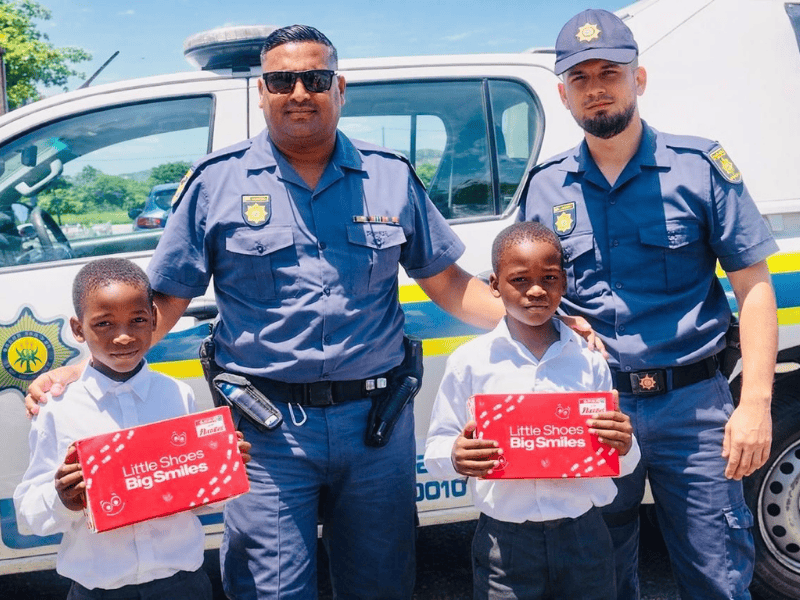 Two police officers standing with two school kids and their new school shoes