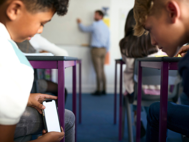 Two pupils playing with a phone in class
