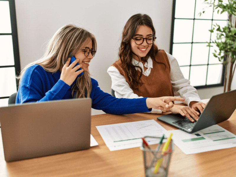 Two young women using their laptops in a corporate setting