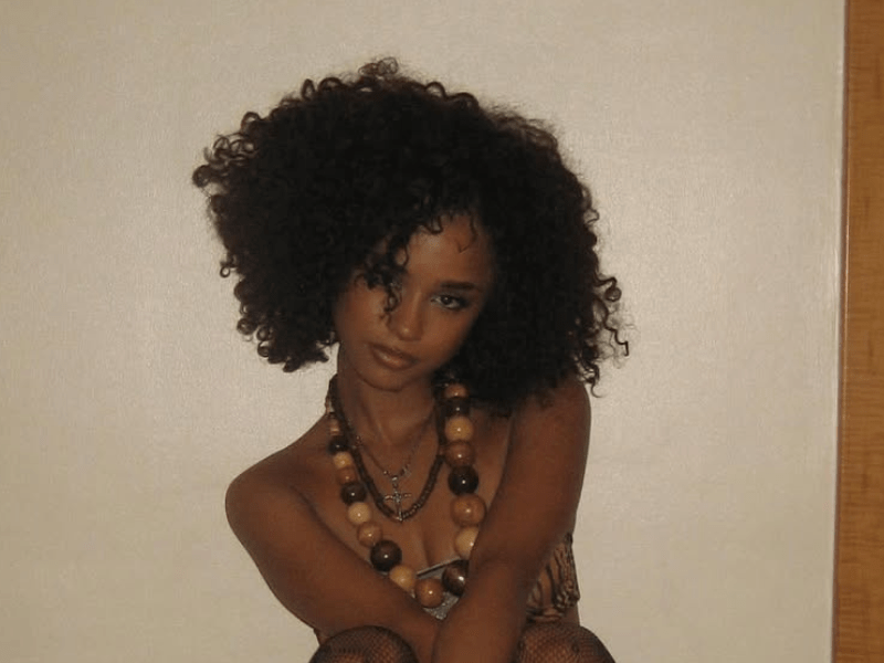 Tyla with voluminous curly hair poses against a wall