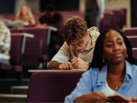 University students taking notes during lecture in a lecture hall