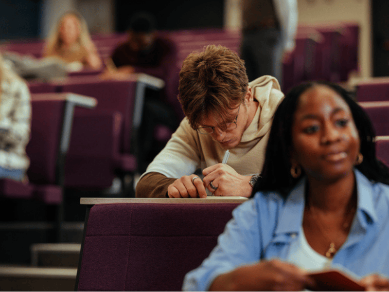 University students taking notes during lecture in a lecture hall
