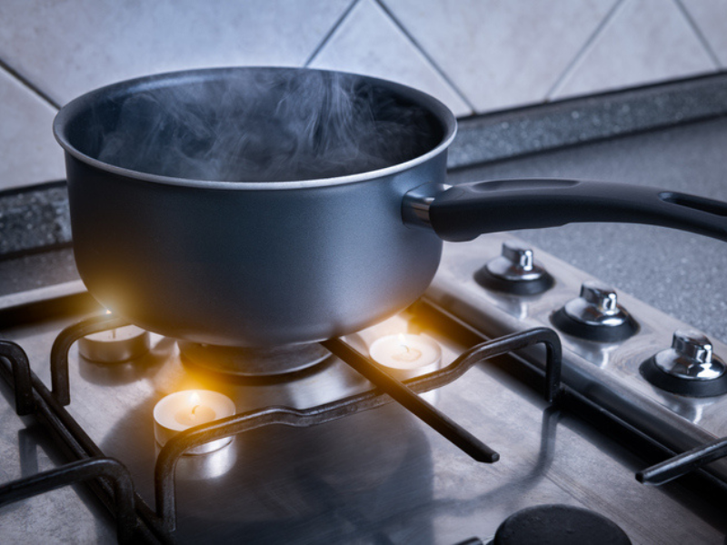 Using candles on a gas stove with a black pot to boil water