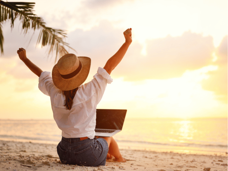 WOMAN WORKING ON LAPTOP ON BEACH