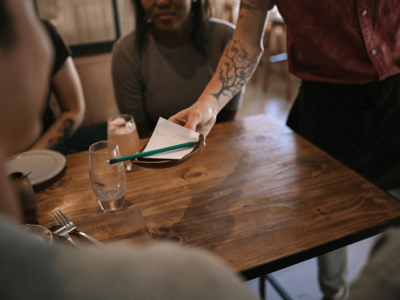 Waiter hands the bill to a table of customers
