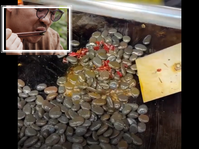 Wok filled with river rocks being fried