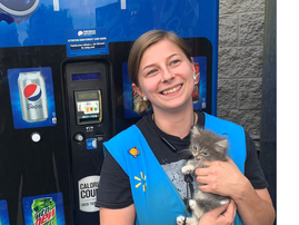 Woman carrying a kitten in front of a vending machine